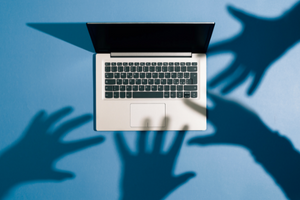 Shadows of four hands above a laptop